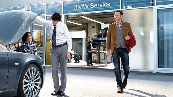 Naprawy gwarancyjne odbywają się w serwisie BMW. Jedno auto przed serwisem i zadowolony Klient inne auto na podnośniku w serwisie BMW.